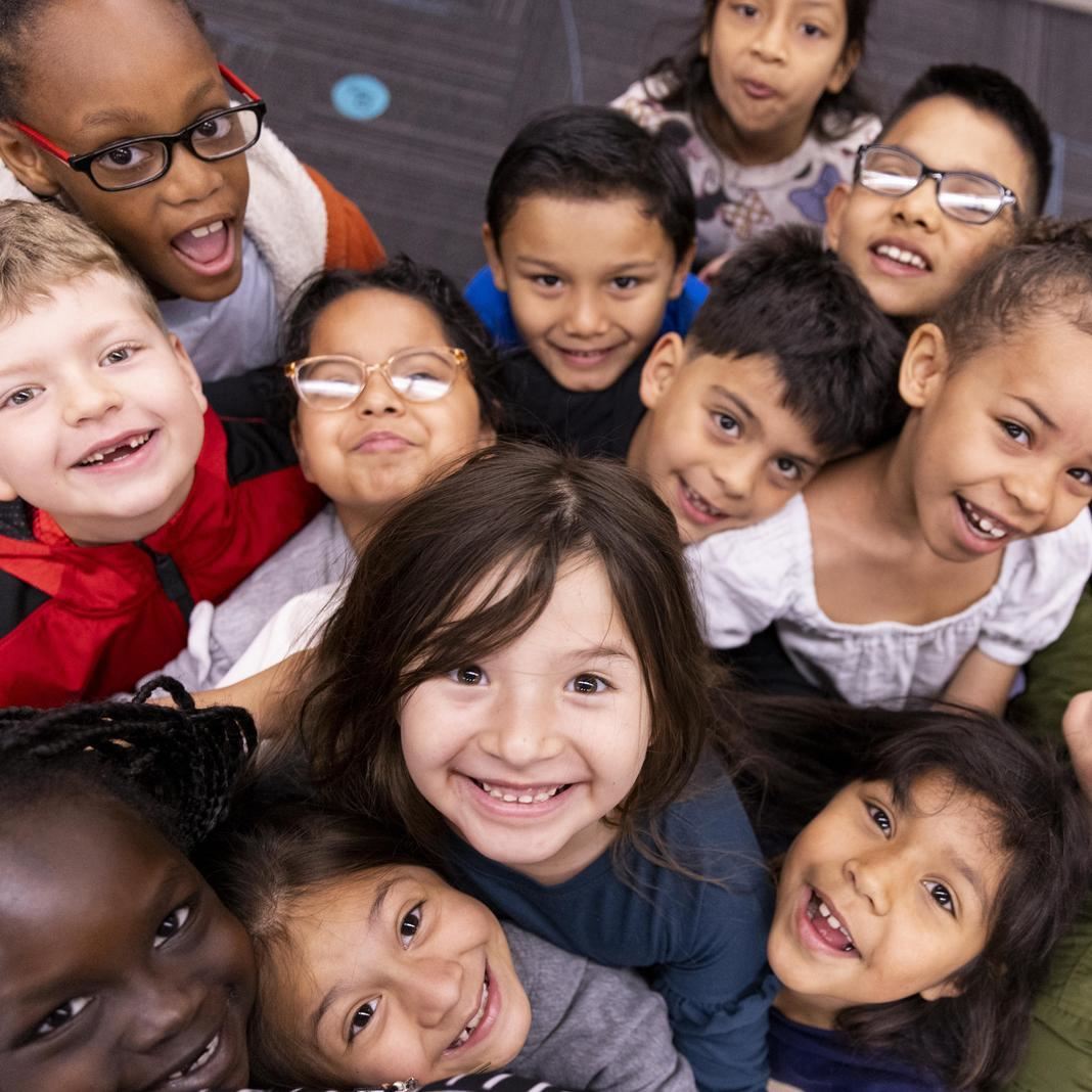  A group of young students look up at the camera and smile